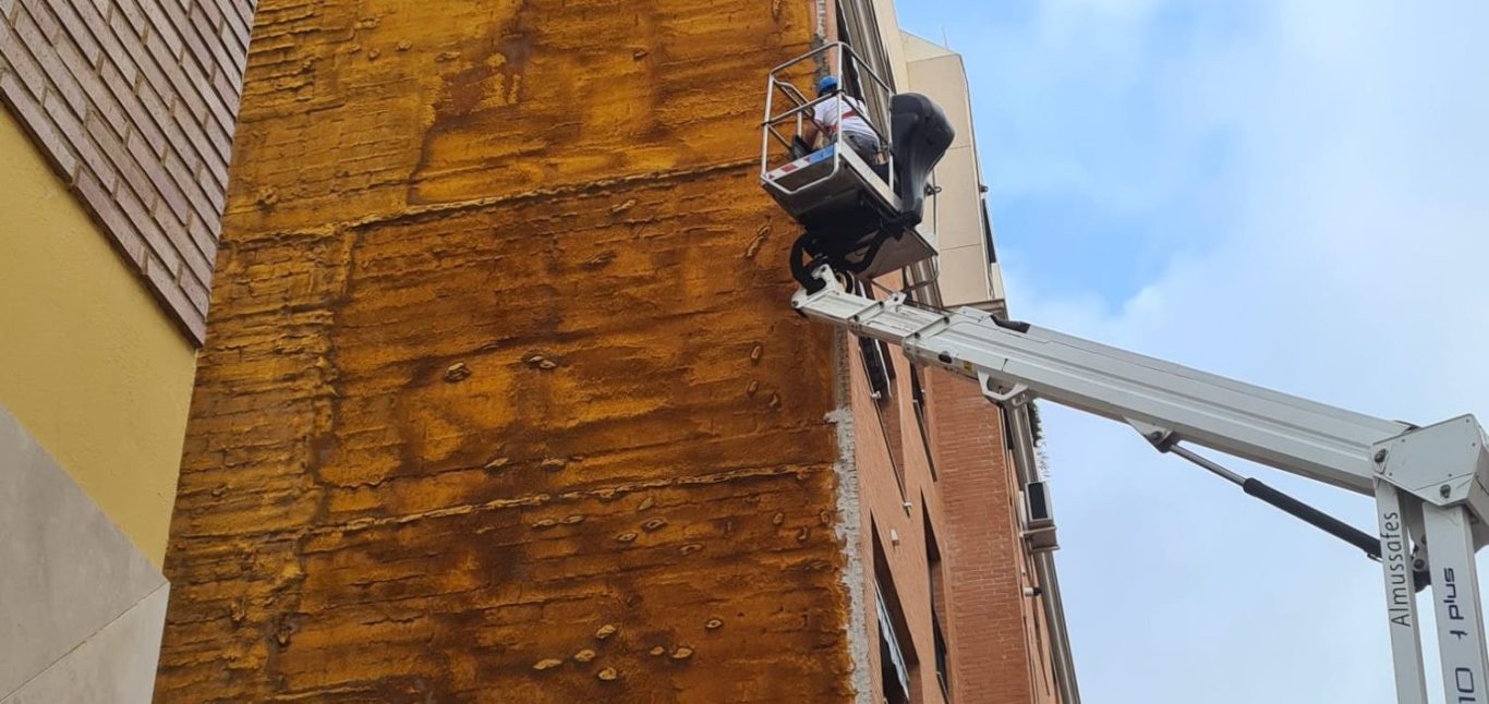 Trabajador en un andamio limpiando la fachada de un edificio.